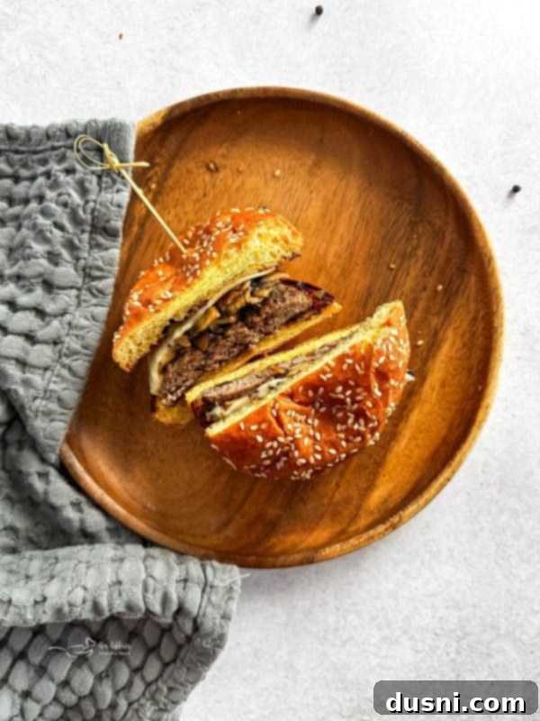 Signature Mushroom Swiss Burger 12 A closeup of a Mushroom Swiss Burger, cut in half, revealing the juicy patty, melted cheese, and mushrooms.