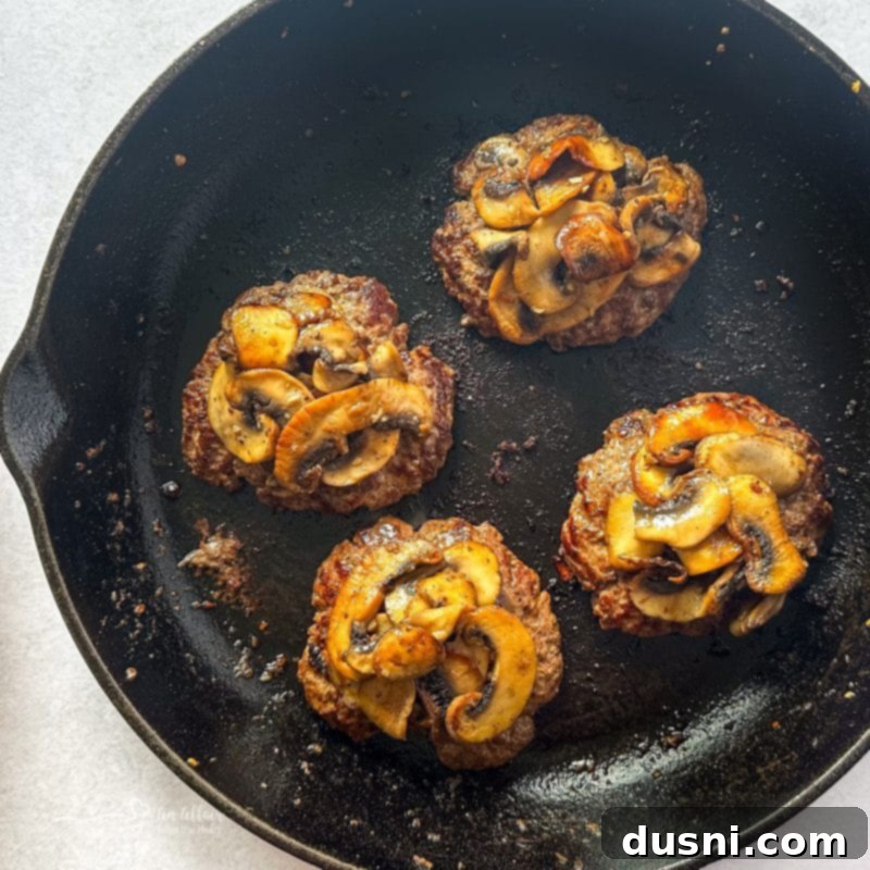 Signature Mushroom Swiss Burger 3 Close-up of a perfectly cooked Mushroom Swiss Burger patty with melted cheese and sautéed mushrooms.