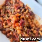 Hearty Five-Bean Bake 12 Five Bean Baked Beans up close on a wooden serving spoon