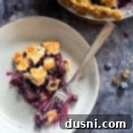 Golden Baked Blueberry Bliss 18 Close up of a slice of blueberry pie and a fork on a white plate