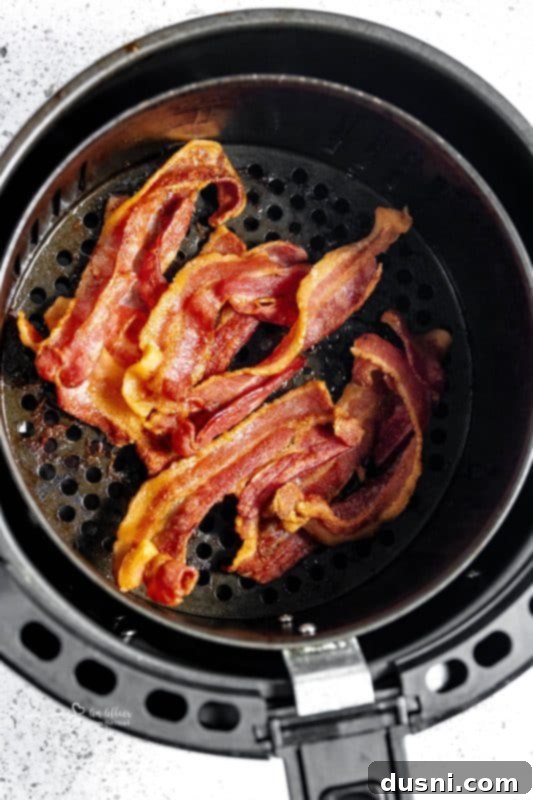 Perfectly Crispy Air Fryer Bacon 2 Air Fryer Bacon cooking in an air fryer basket