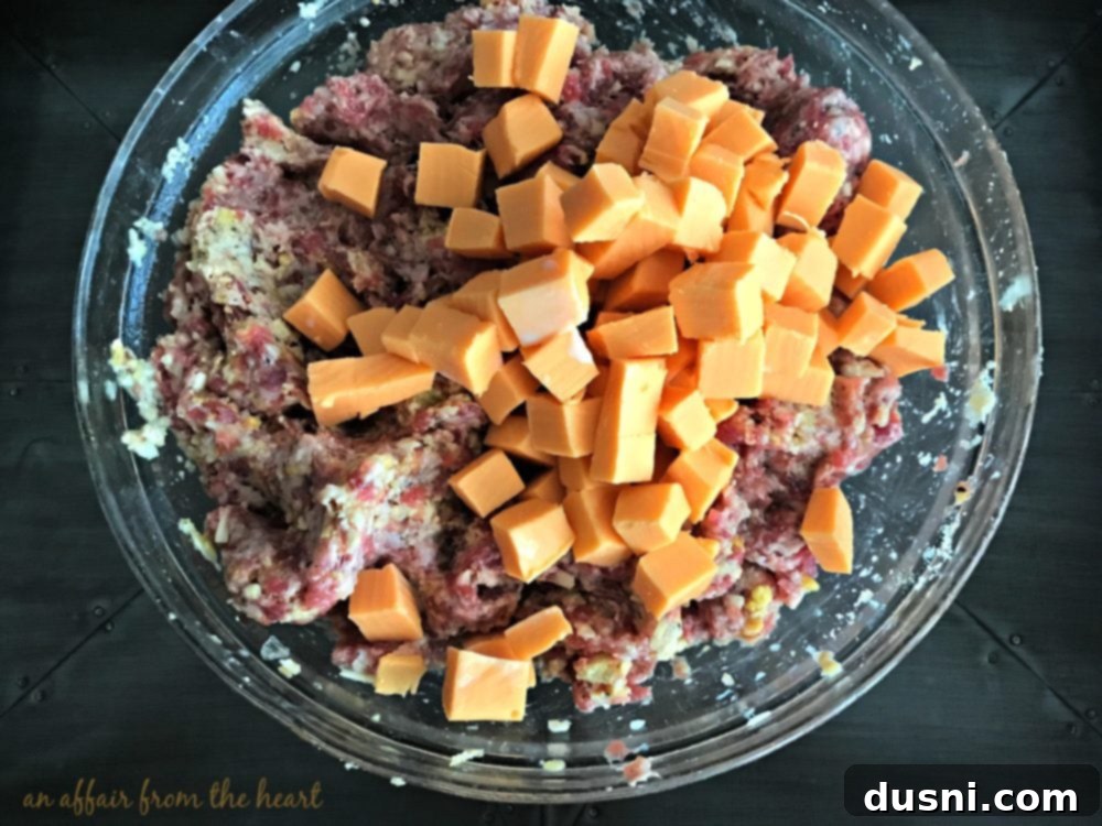 Moms Hearty Pork Sausage Meatloaf 6 Chef's hand carefully adding cubed Velveeta cheese to the meatloaf mixture