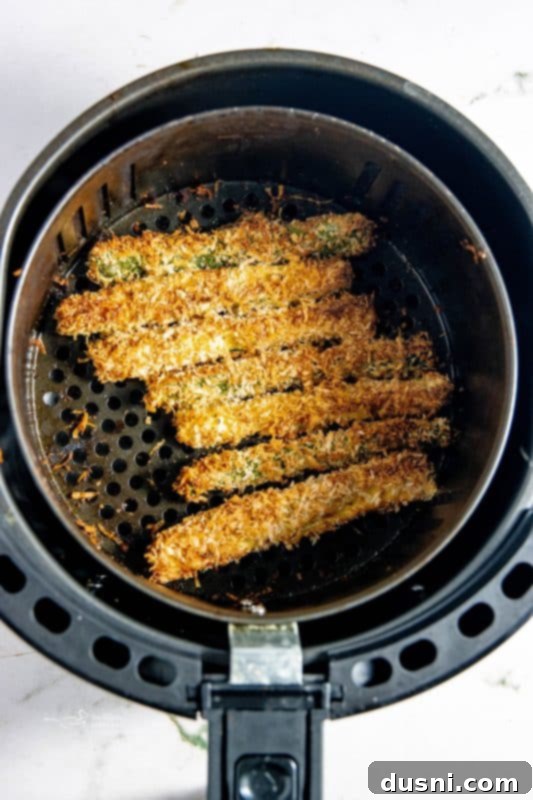 Crispy Air Fryer Zucchini Fries 13 Zucchini fries in an air fryer basket, ready to cook