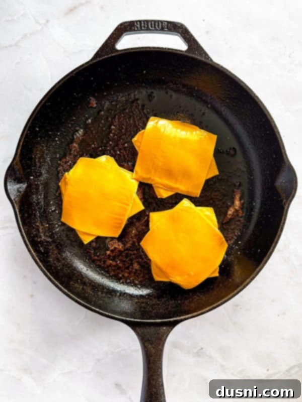 Step-by-step image of placing cheese on cooked burger patties.