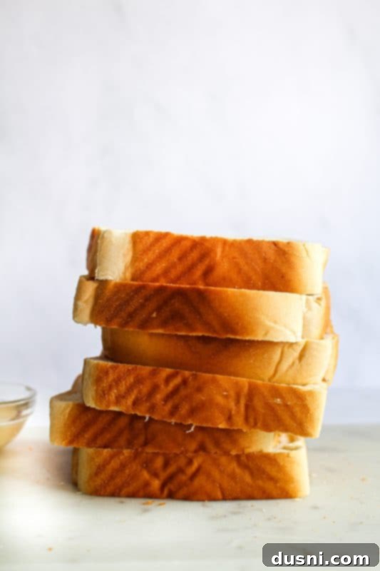Close up of a Dunker Burger being dipped into a small bowl of homemade au jus. The golden Texas Toast and melted cheese are visible.