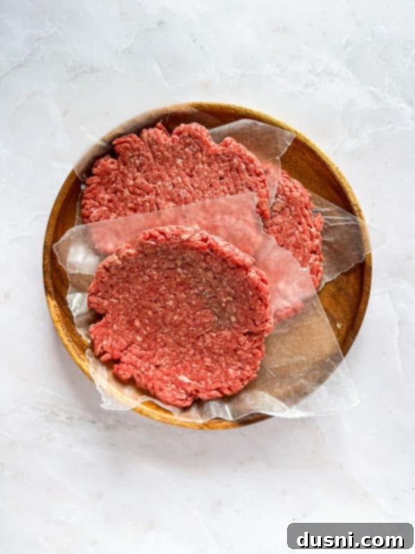 Close up of a perfectly cooked burger patty with two slices of melted American cheese on top, ready for assembly.