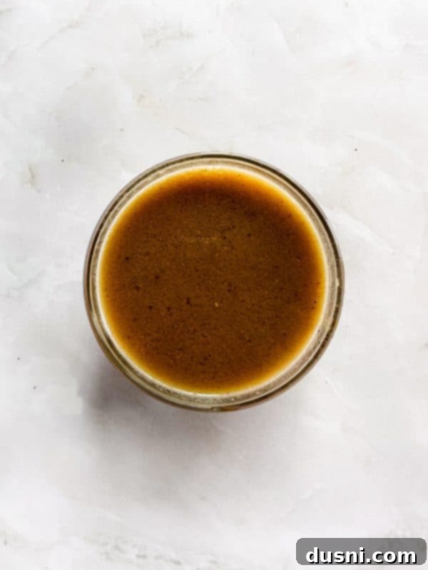 Step-by-step image of making au jus: whisking beef stock into the roux in a saucepan.