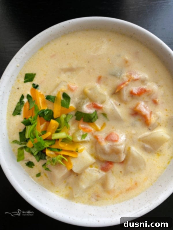 Top view of cheesy potato soup in white bowl