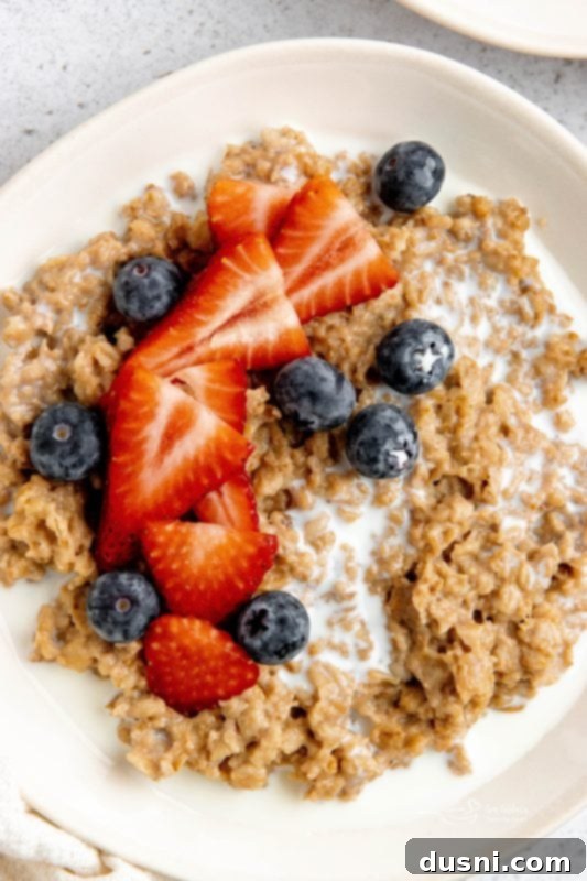 Styled bowl of Instant Pot Cinnamon Oatmeal, with a spoon and toppings on the side.
