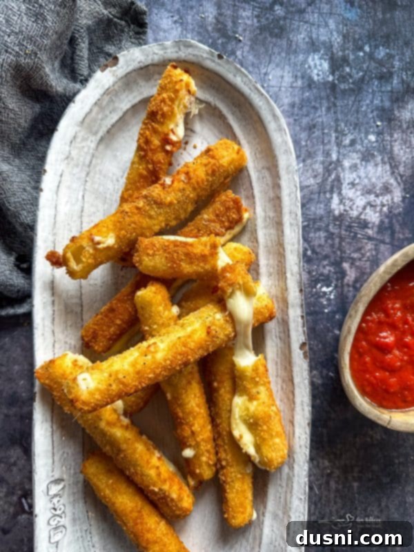 Platter of golden homemade mozzarella sticks, a delicious snack.