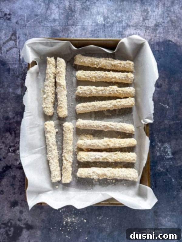 Second step of breading: dipping mozzarella stick in breadcrumbs.