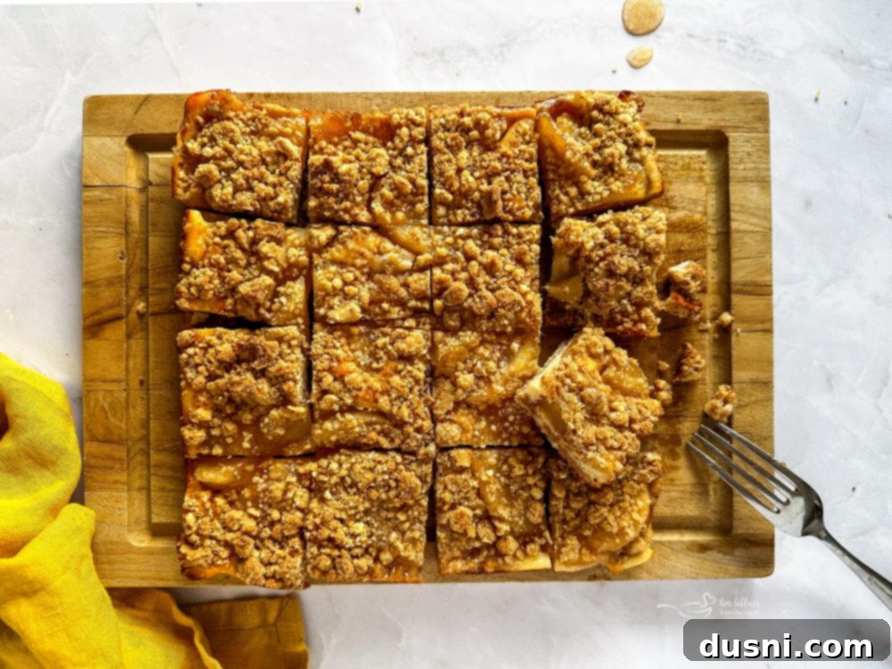 Two rows of freshly baked Apple Pie Crumb Bars on a baking sheet, showcasing golden brown tops