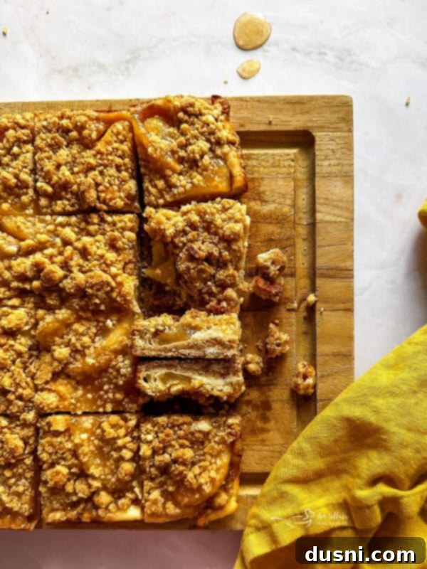 A close-up shot of a single Apple Pie Crumb Bar, showing the layers of crust, filling, and crumb topping