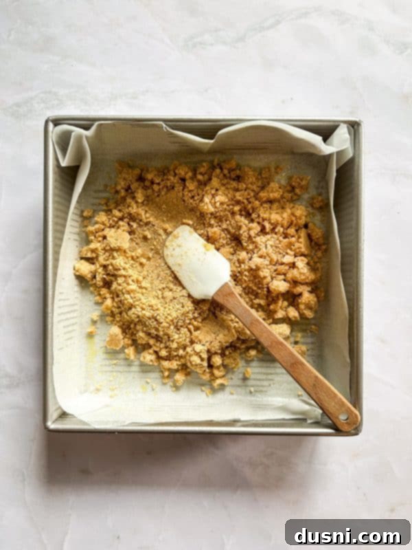 Melted butter being poured into the dry crust ingredients in a mixing bowl