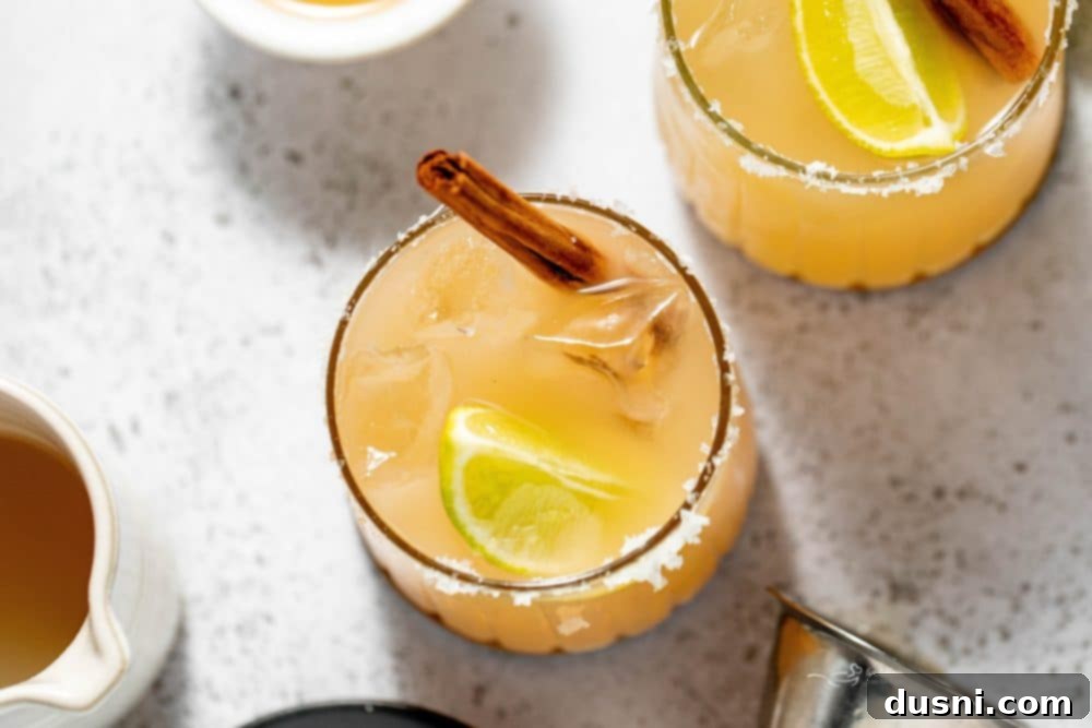 Apple Cider Margarita 12 Overhead shot of two Apple Cider Margaritas with cinnamon sticks and autumn decorations.