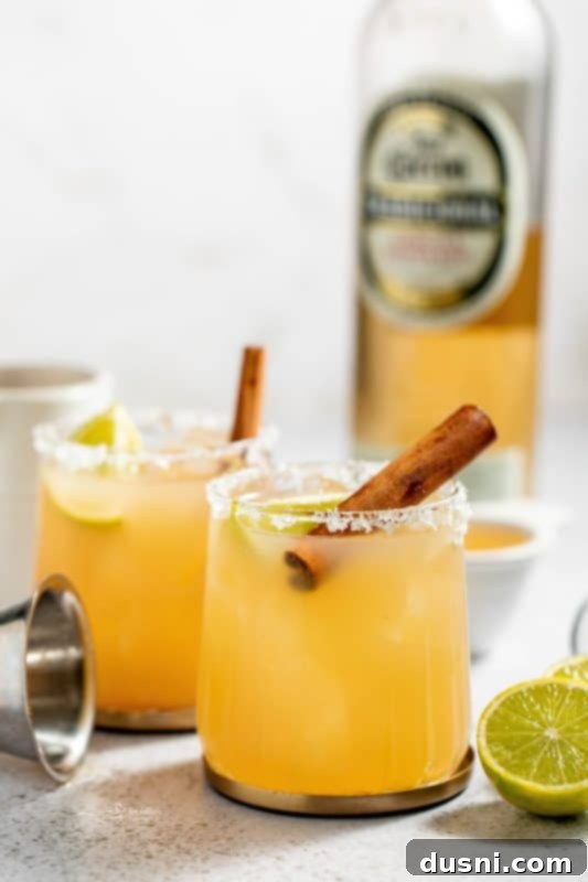 Apple Cider Margarita 3 Two Apple Cider Margaritas with fall foliage in the background, showcasing the beautiful autumn ambiance.