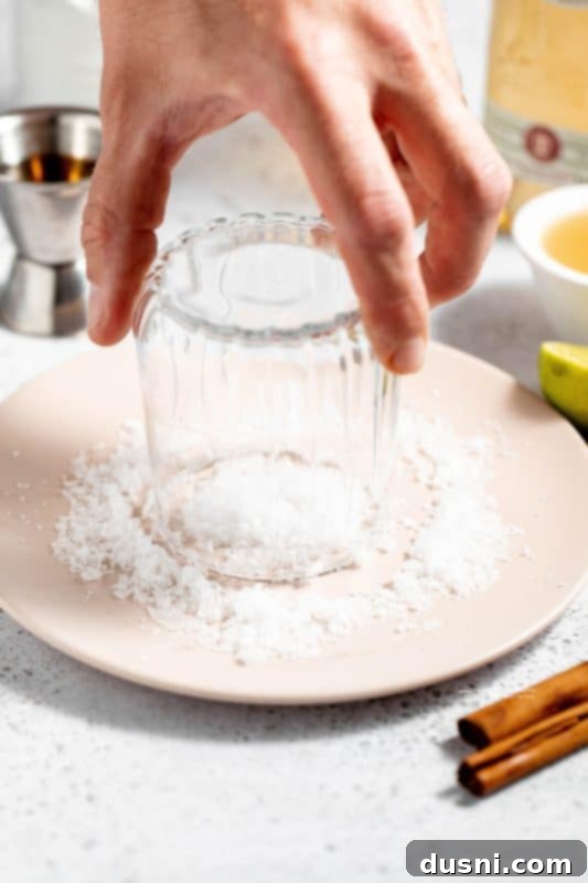 Apple Cider Margarita 6 A hand rubbing a lime wedge around the rim of a cocktail glass.