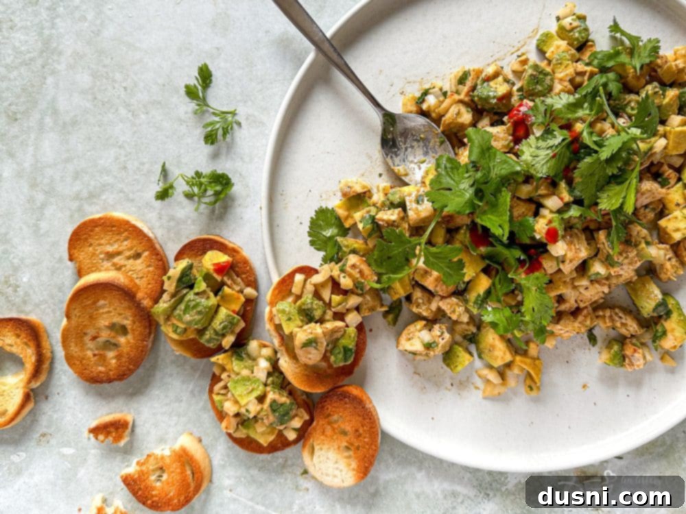 Irresistible Avocado Chicken Salad Dip 4 Avocado Chicken Salad Dip served in a large bowl with various dippers like crackers, bell pepper, and cucumber slices.