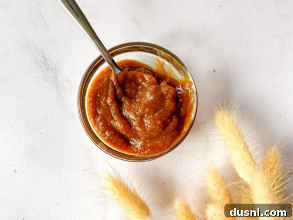Overhead shot of pumpkin butter in a rustic bowl, surrounded by autumn leaves.