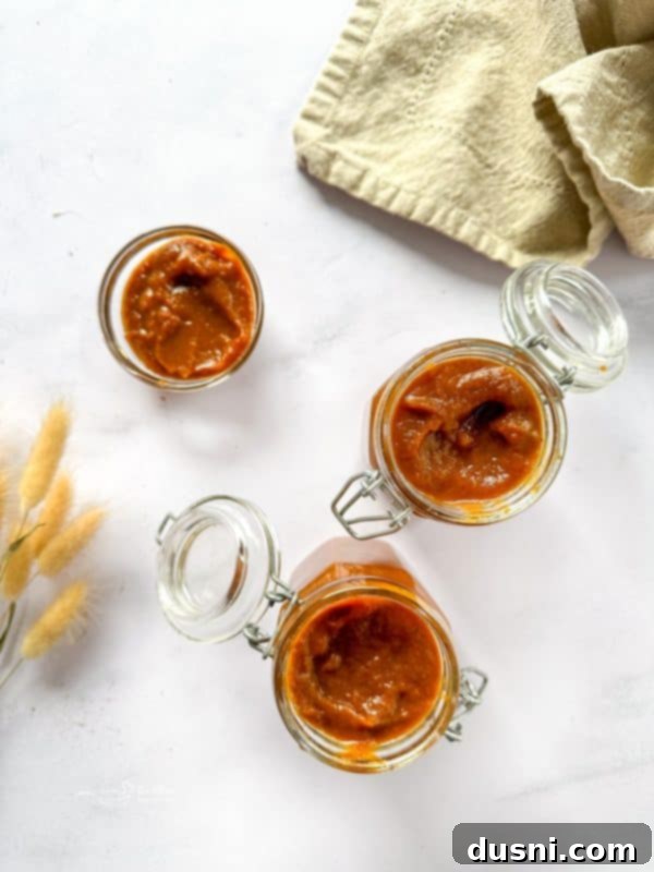 Jar of homemade pumpkin butter with a wooden spoon, perfect for fall