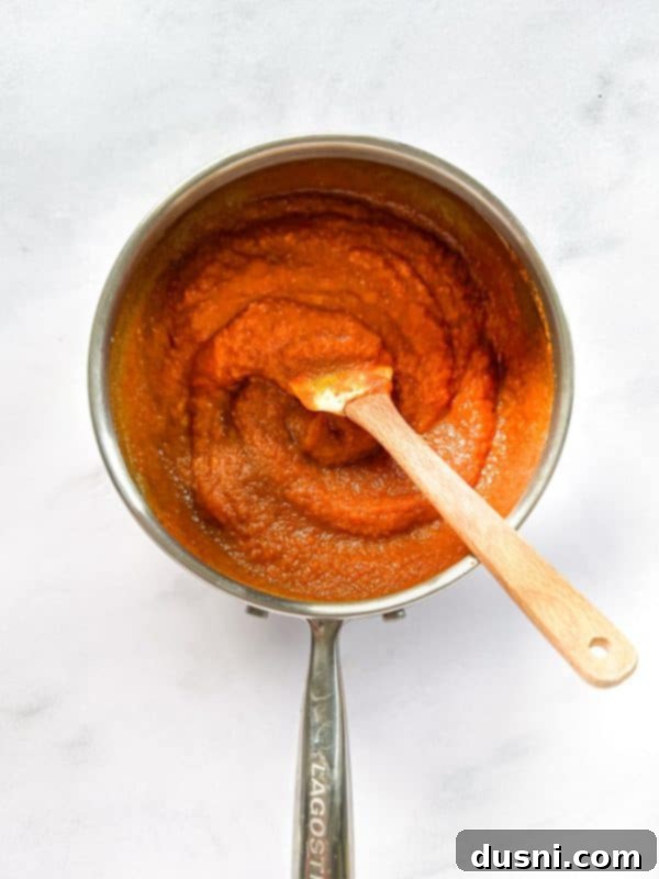 Pumpkin butter mixture coming to a boil on the stove, beginning to thicken.