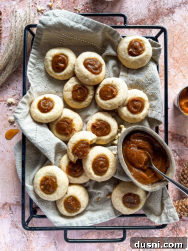 Snickerdoodle Thumbprint Cookies with pumpkin butter filling, arranged on a rustic wooden tray.