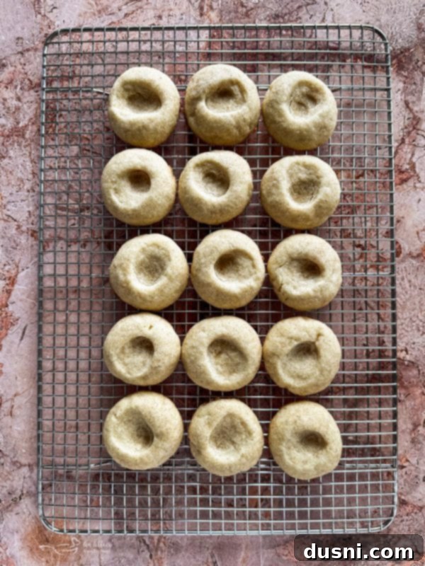 Freshly baked snickerdoodle thumbprint cookies cooling on a wire rack.