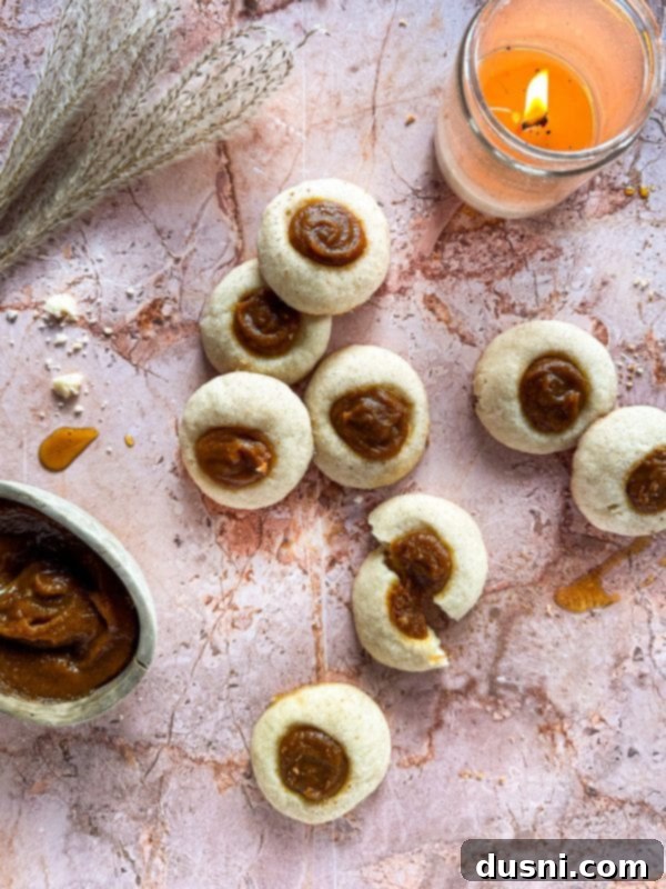 Snickerdoodle thumbprint cookies with pumpkin butter on a marble surface.