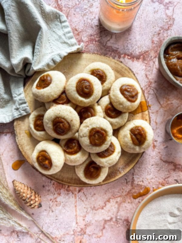 Snickerdoodle thumbprint cookies cooling on a wire rack, ready for their pumpkin filling.