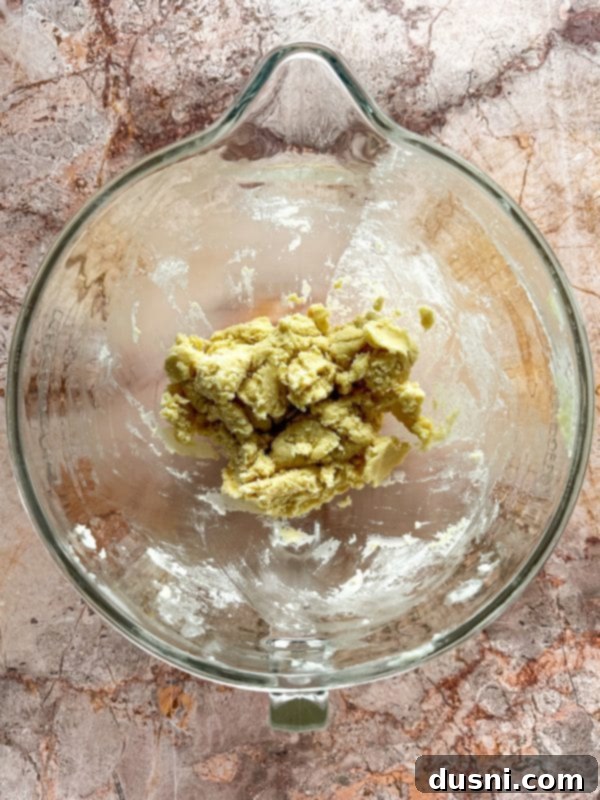 Adding egg yolks and vanilla extract to the creamed butter and sugar mixture.