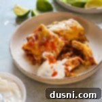 Comforting Slow Cooker Smothered Burritos 15 Slow Cooker Smothered Burritos and sour cream on a plate.
