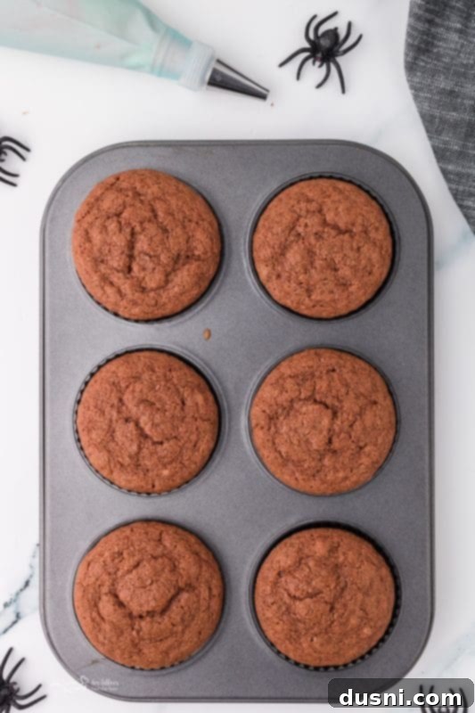 Ghoulish Grey Matter Cupcakes 12 A visual step-by-step image showing cupcake liners being filled with batter, illustrating the preparation before baking.