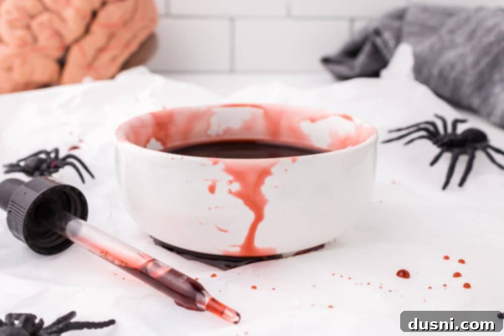 Ghoulish Grey Matter Cupcakes 20 A festive close-up of a Halloween Brain Cupcake, prominently featuring the pink brain frosting and edible blood, with decorative spiders and webs in the background, setting a spooky and celebratory mood for the dessert.