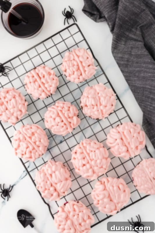 Ghoulish Grey Matter Cupcakes 21 An overhead shot of a single Halloween Brain Cupcake with a small plastic spider on the frosting, adding an extra spooky touch. The intricate brain piping and edible blood are clearly visible, creating a delightful and creepy Halloween dessert.