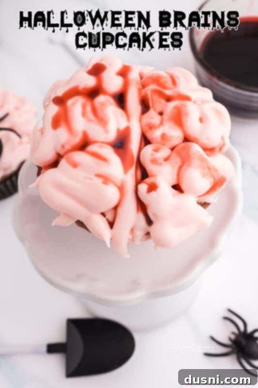 Ghoulish Grey Matter Cupcakes 23 A high-quality hero shot of a Halloween Brain Cupcake, prominently featured with its pink brain frosting and edible blood, on a dark background. This image sets the tone for the article, highlighting the spooky and delicious nature of the dessert.