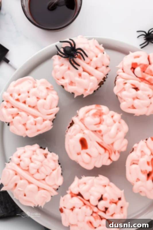Ghoulish Grey Matter Cupcakes 4 A single Halloween Brain Cupcake presented close-up, highlighting the detailed frosting technique and the shimmering edible blood. The background is blurred, drawing all attention to the ghoulishly appealing dessert, ready for a Halloween feast.