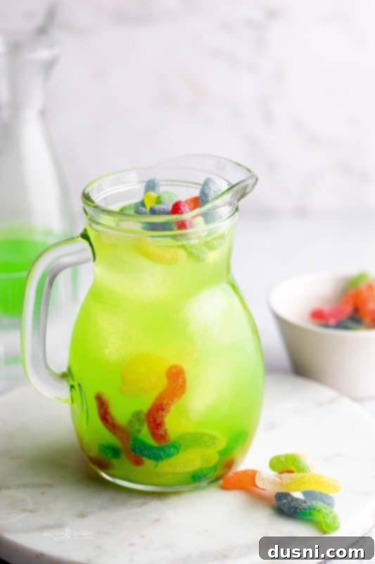 Pouring Green Gatorade into a pitcher with ice and gummy worms