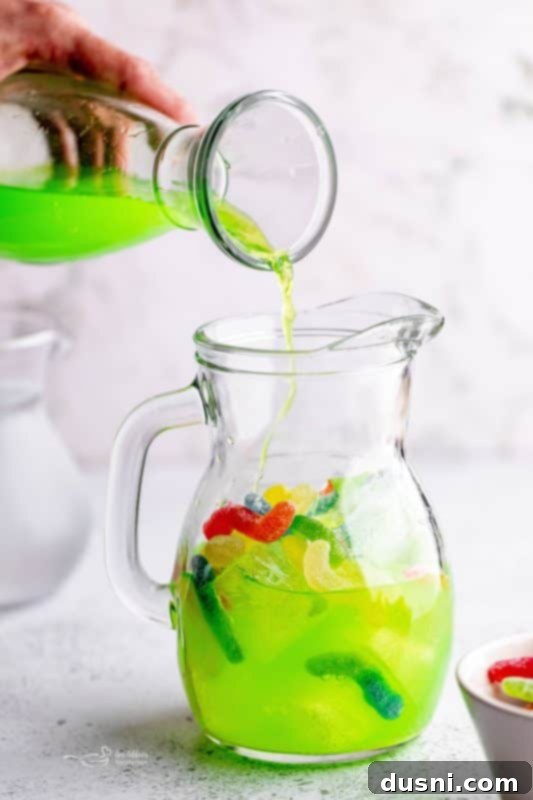 Pouring Gatorade into a pitcher with ice and sour worms