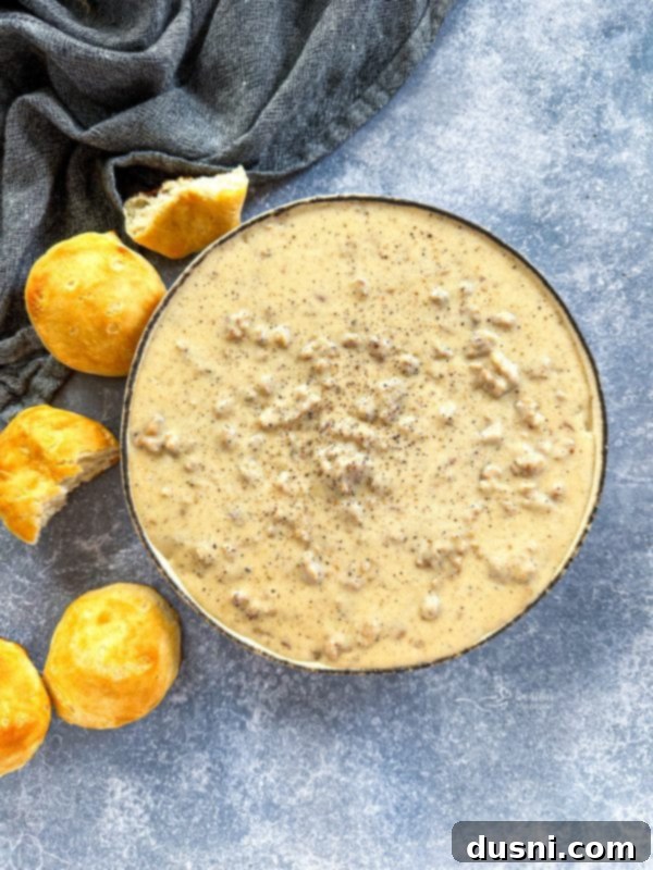 A serving of classic Southern biscuits and homemade sausage gravy on a plate, with a fork ready to dig in.