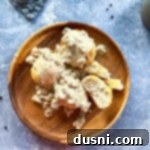 Sausage gravy and biscuits on a brown plate.