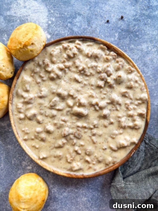 Close-up of a serving of homemade sausage gravy, showing its rich, thick, and creamy texture with visible pieces of browned sausage.