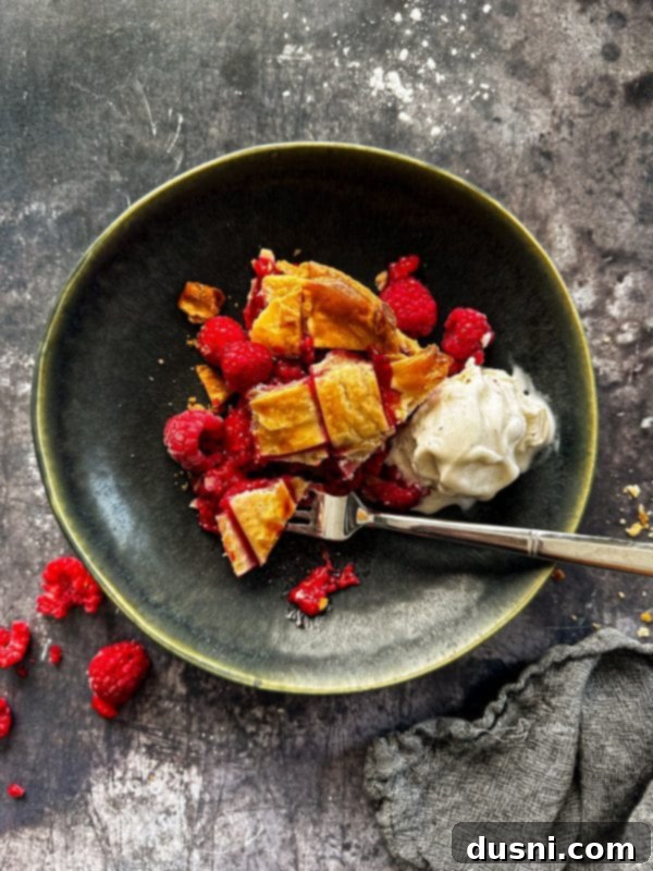 Sun-Kissed Raspberry Pie 2 Fresh raspberry pie with a lattice top and scoop of ice cream on a green plate
