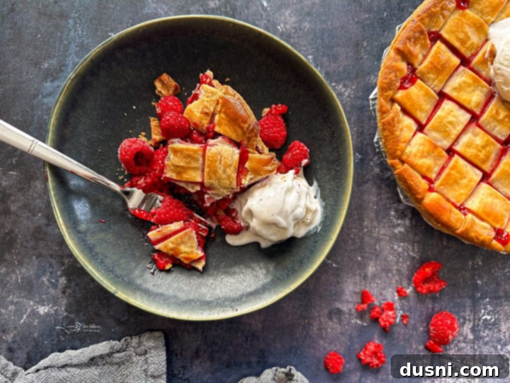 Sun-Kissed Raspberry Pie 4 Close-up of a slice of raspberry pie with a lattice top and ice cream