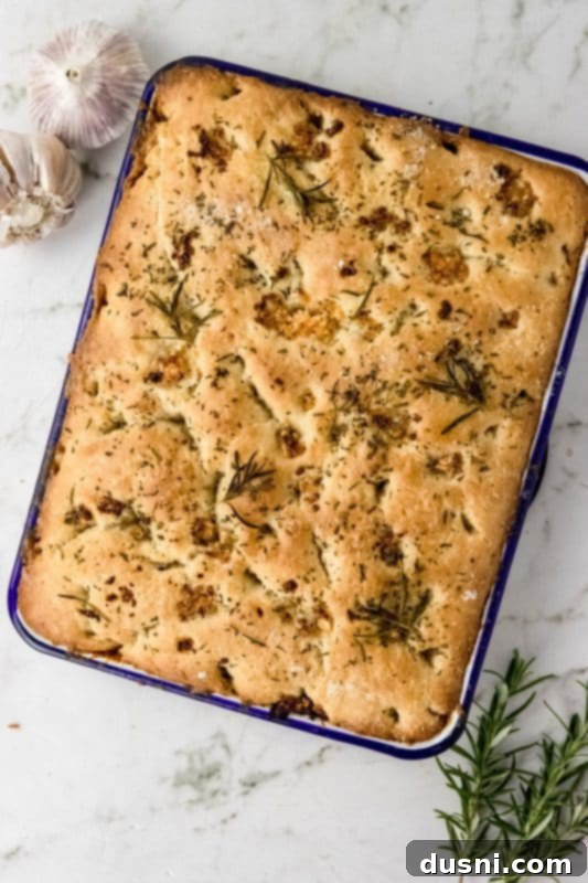 Freshly baked focaccia bread with garlic and rosemary, cooling on a rack