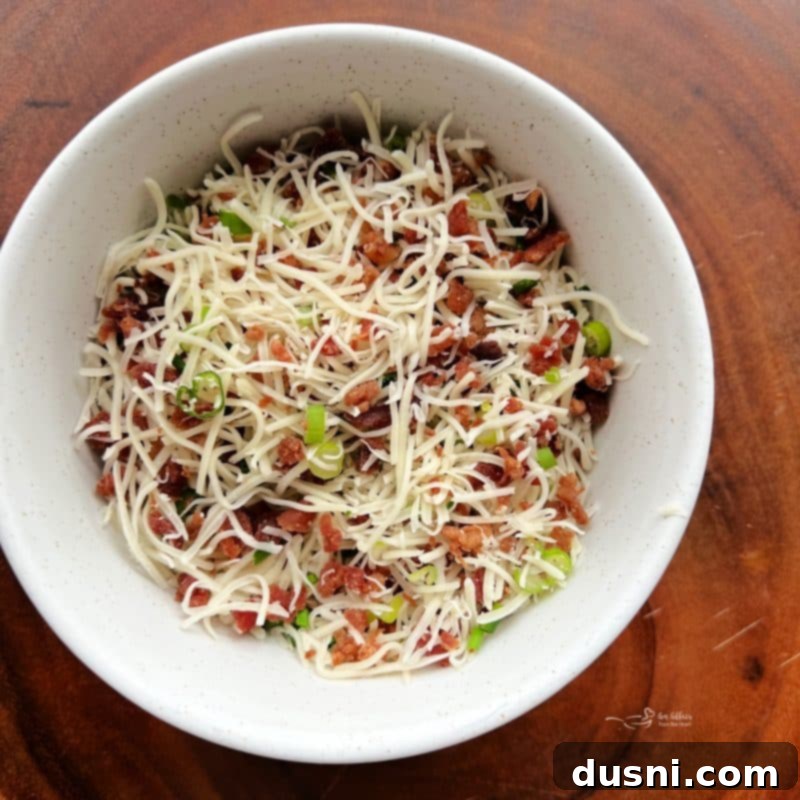 Ingredients for the outer coating mixture (green onion, chives, bacon bits, Swiss cheese) in a small white bowl.