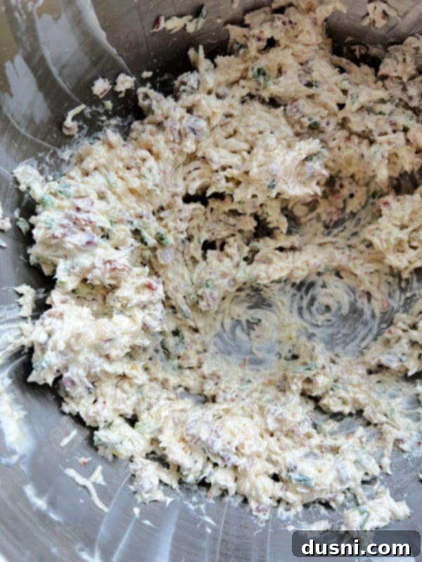 The cheese ball mixture after all ingredients are combined, showing flecks of green, red, and yellow.