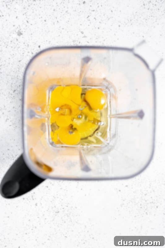 Homemade Blender Eggnog 7 Adding fresh eggs to a blender cup, the first step in making homemade eggnog.