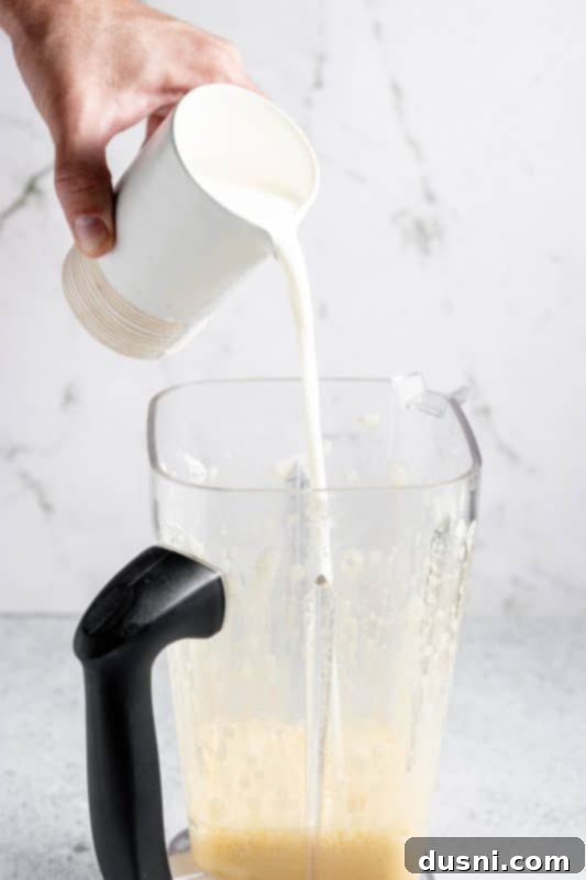 Homemade Blender Eggnog 10 Adding whole milk to the blender with the egg and syrup mixture.