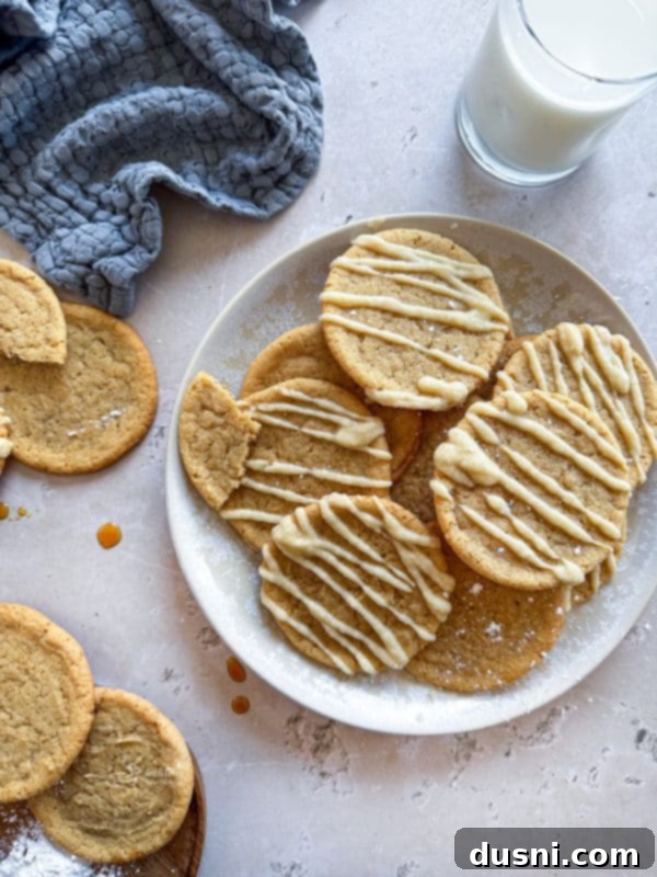 Three Iced Maple Sugar Cookies on a wooden board with fall leaves