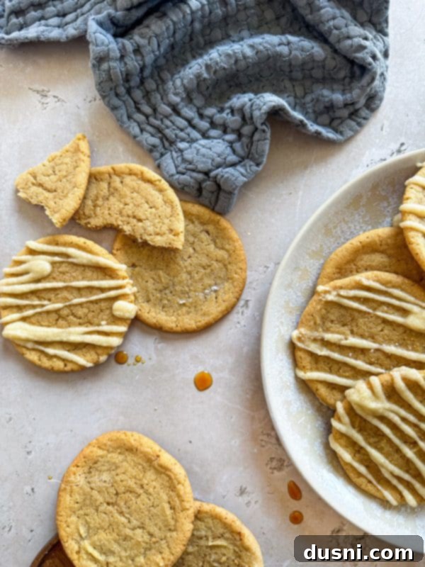 Maple icing being drizzled over cooled maple sugar cookies on a wire rack
